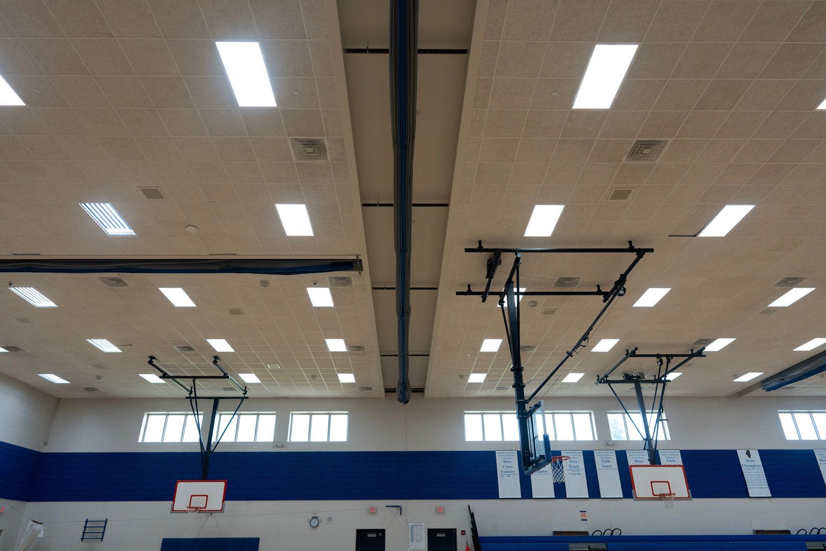 A gym with a basketball hoop and a ceiling that has a lot of lights on it