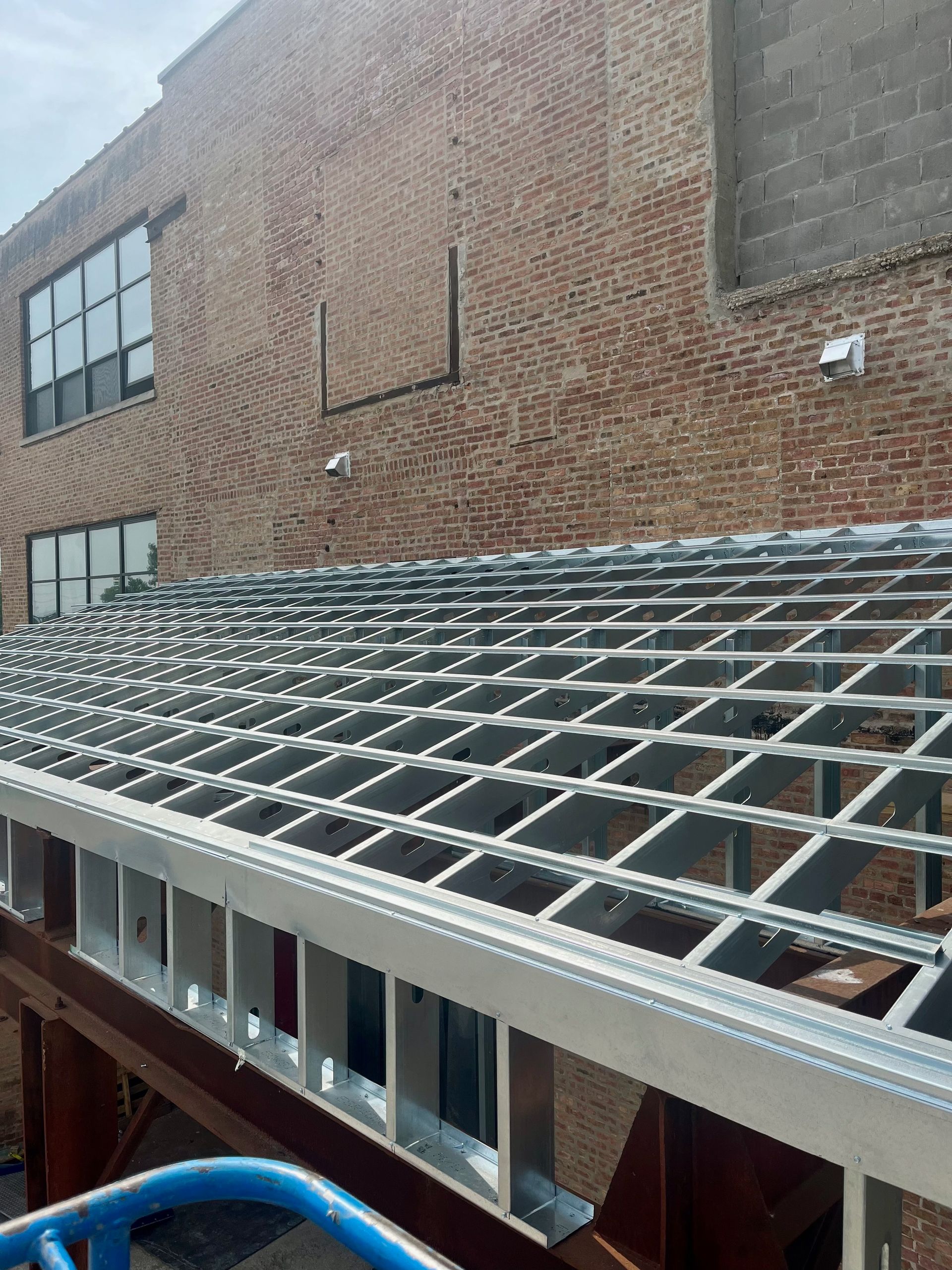 A metal structure is being built on the side of a brick building.