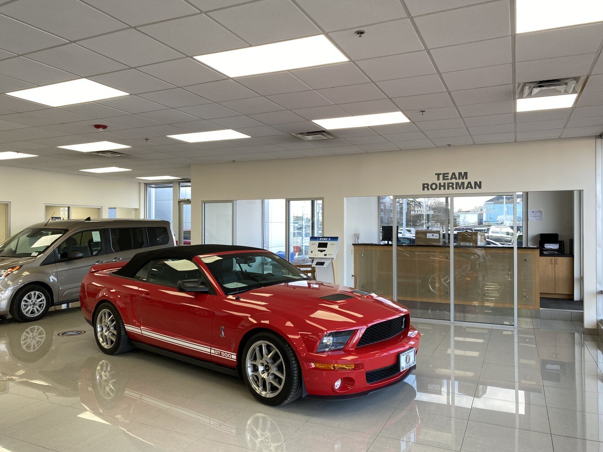 A red mustang is parked in a car dealership