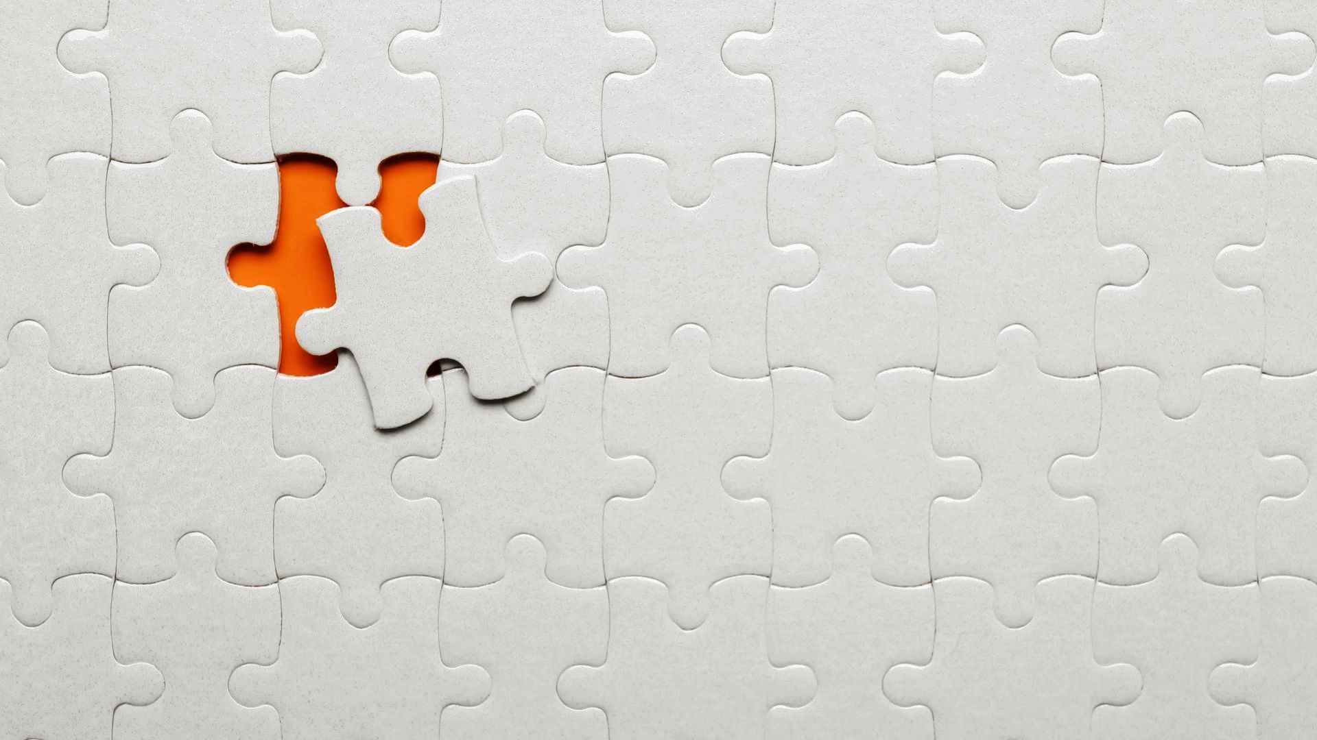 A white puzzle with an orange piece missing.