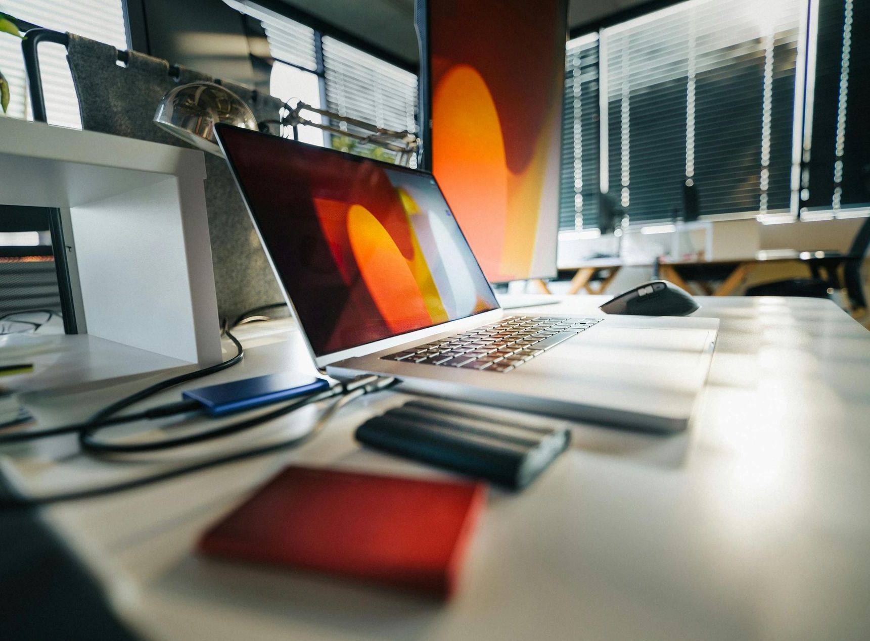 A row of laptops are sitting on a desk in an office.