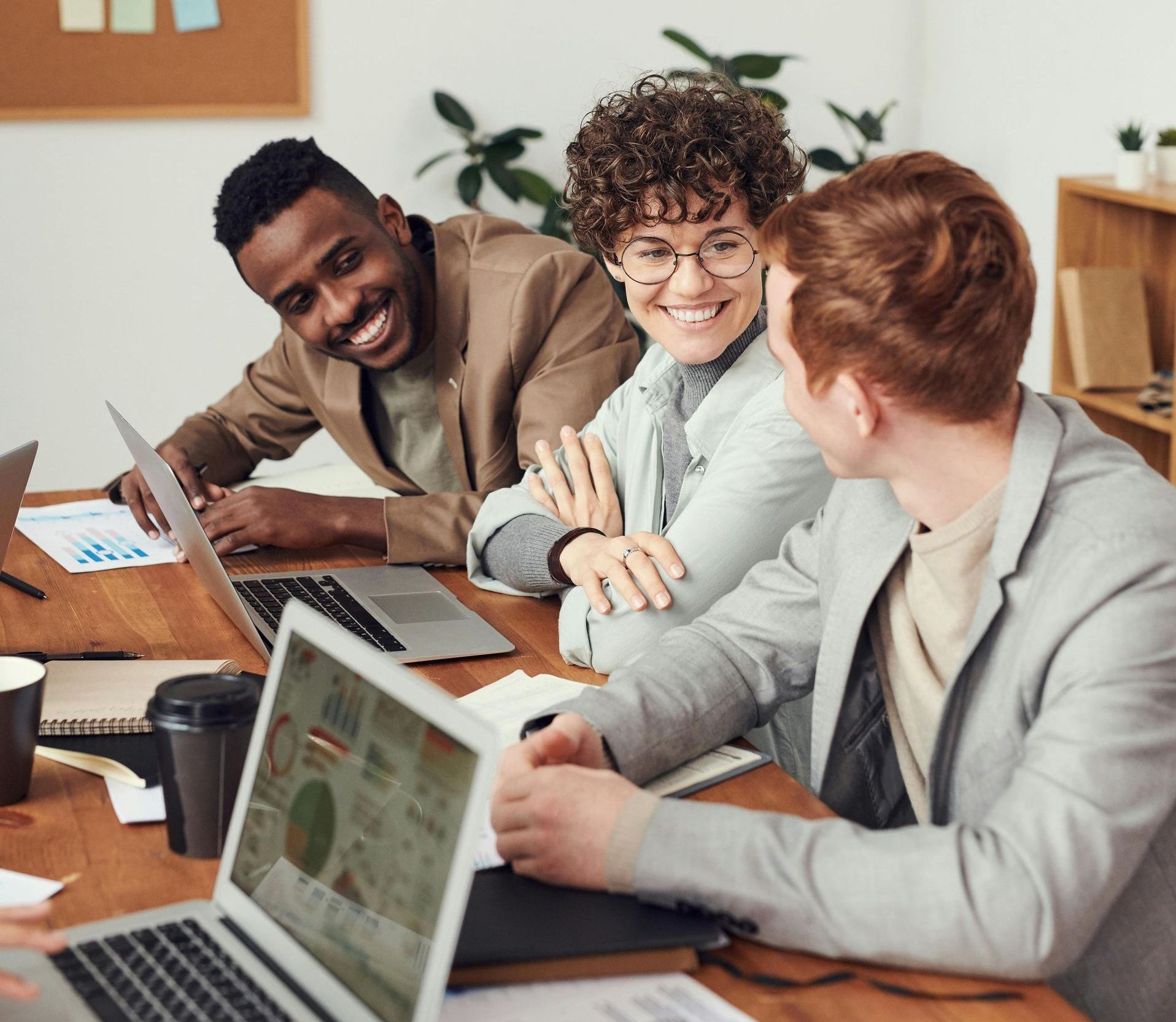 A group of people are sitting around a table with laptops.