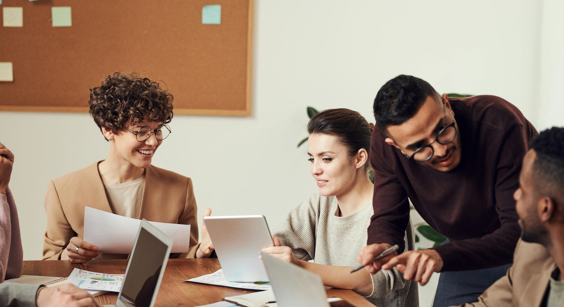 A group of people are sitting around a table looking at laptops.
