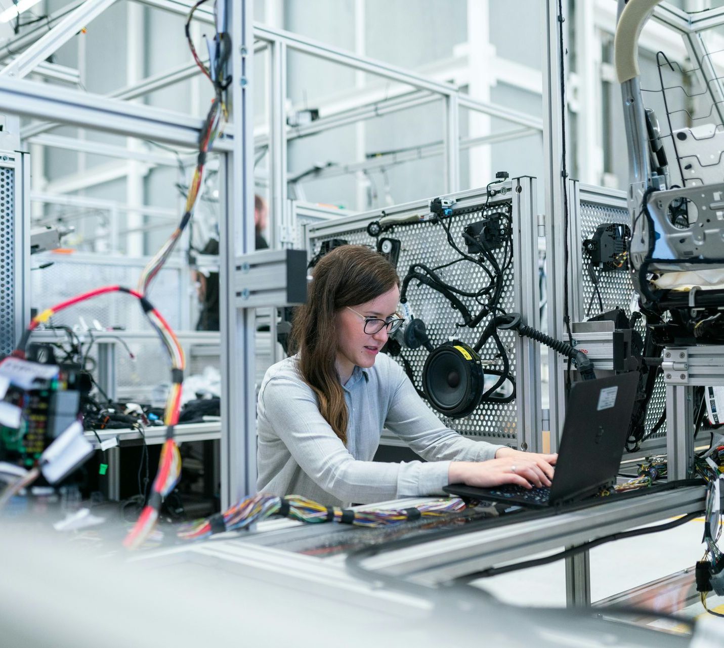 A woman is working on a laptop computer in a factory.
