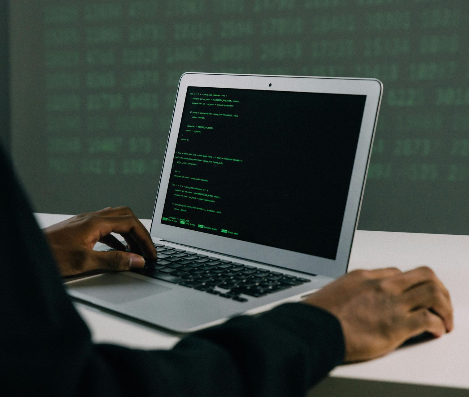 A person is typing on a laptop with a green screen