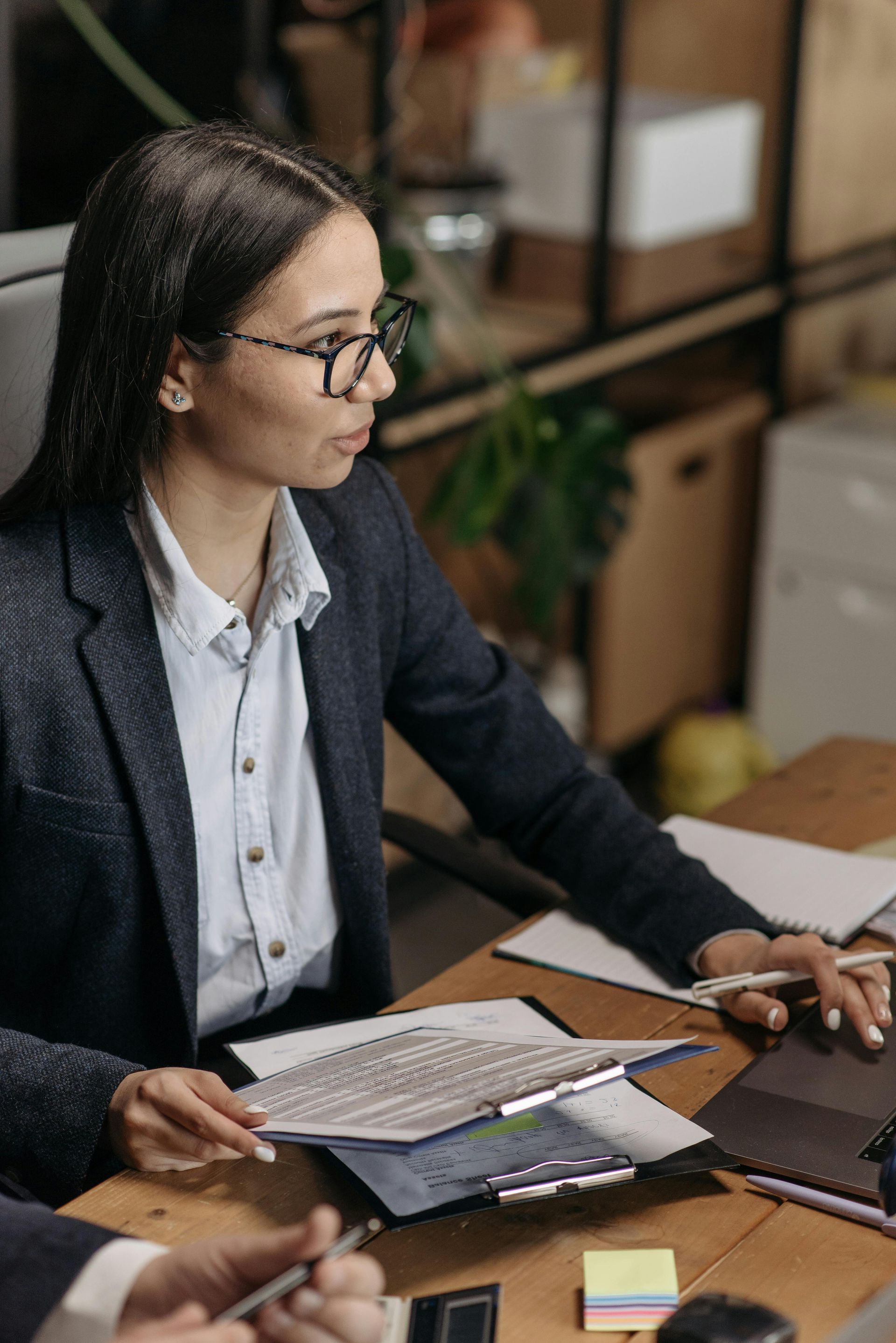 A woman is sitting at a desk looking at a piece of paper.