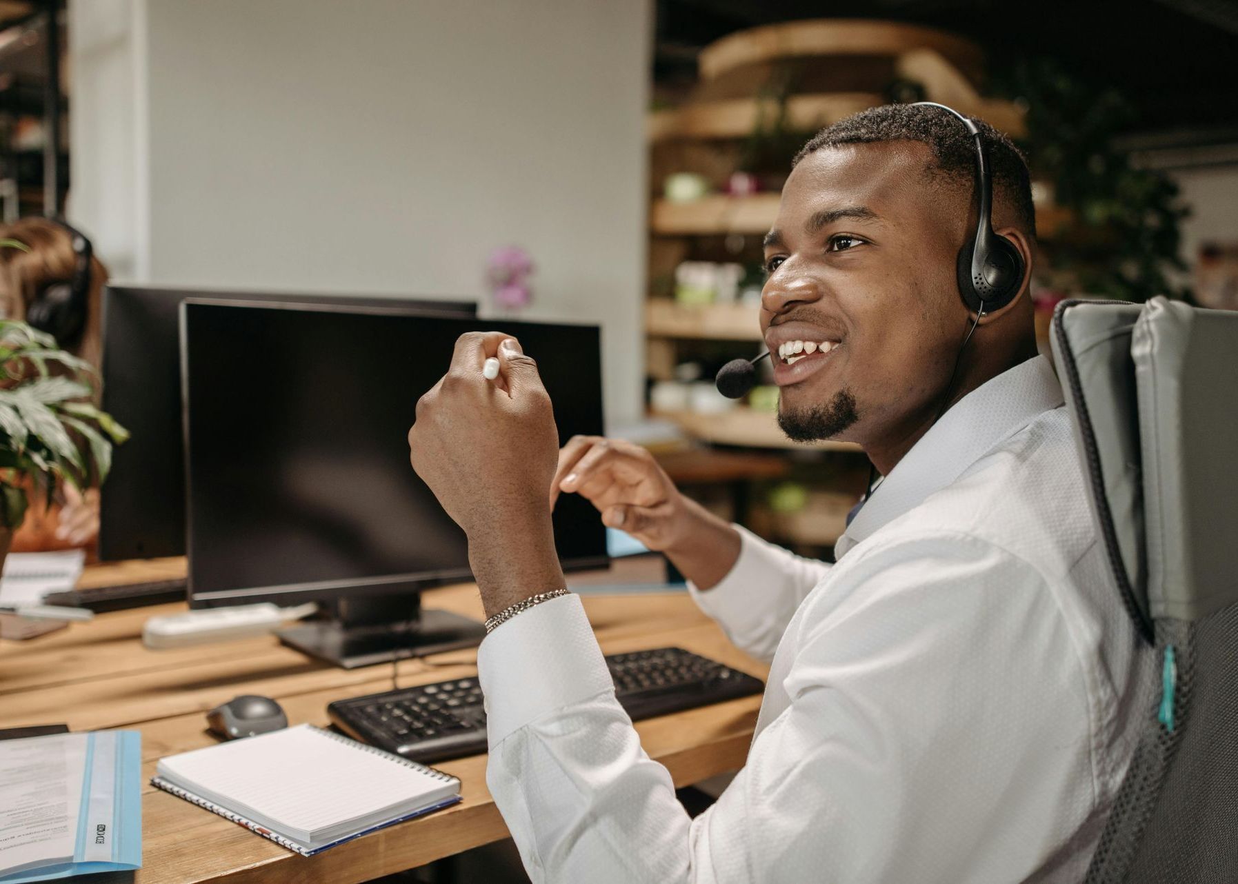 A man wearing a headset is sitting in front of a computer.