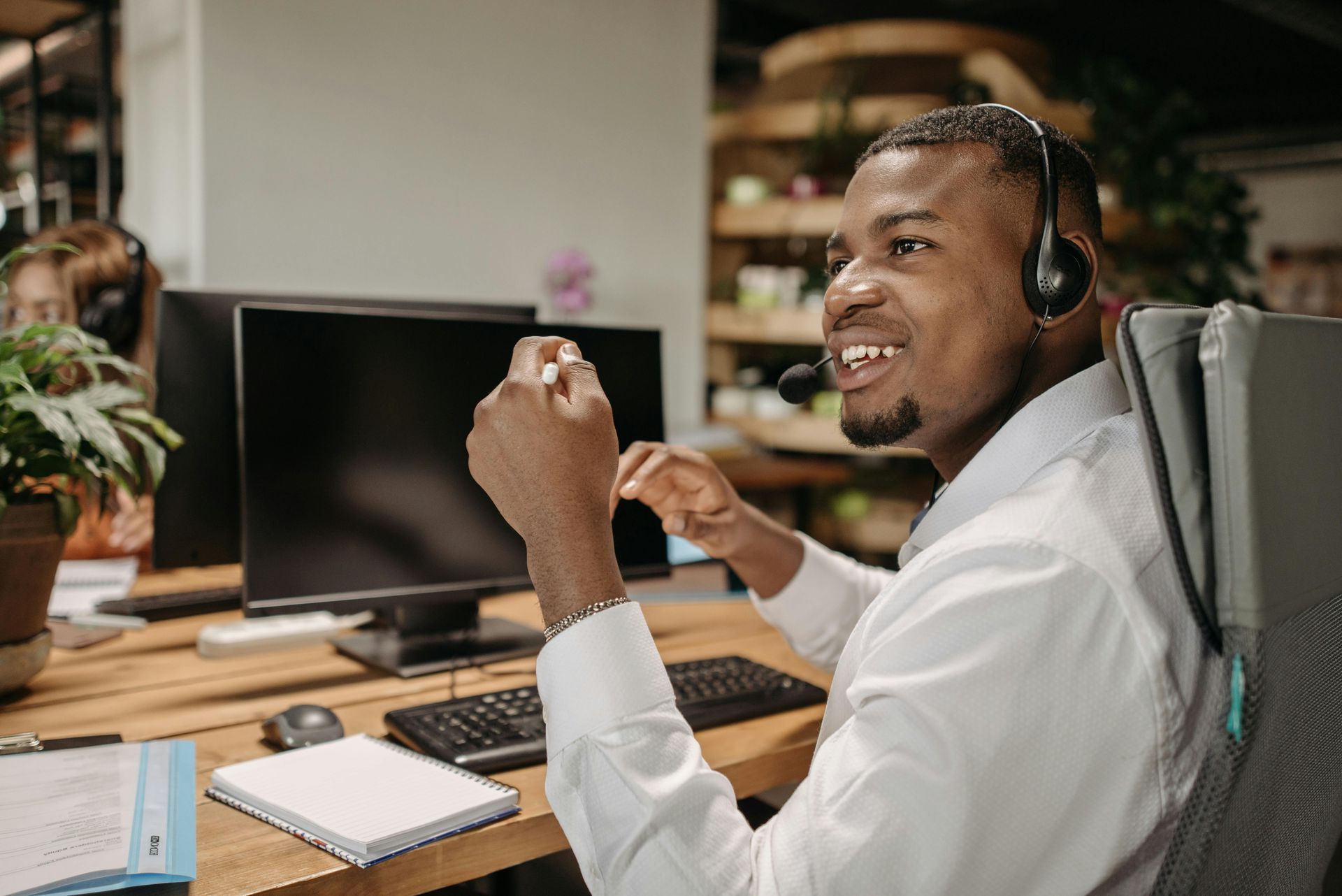 A man wearing a headset is sitting in front of a computer.