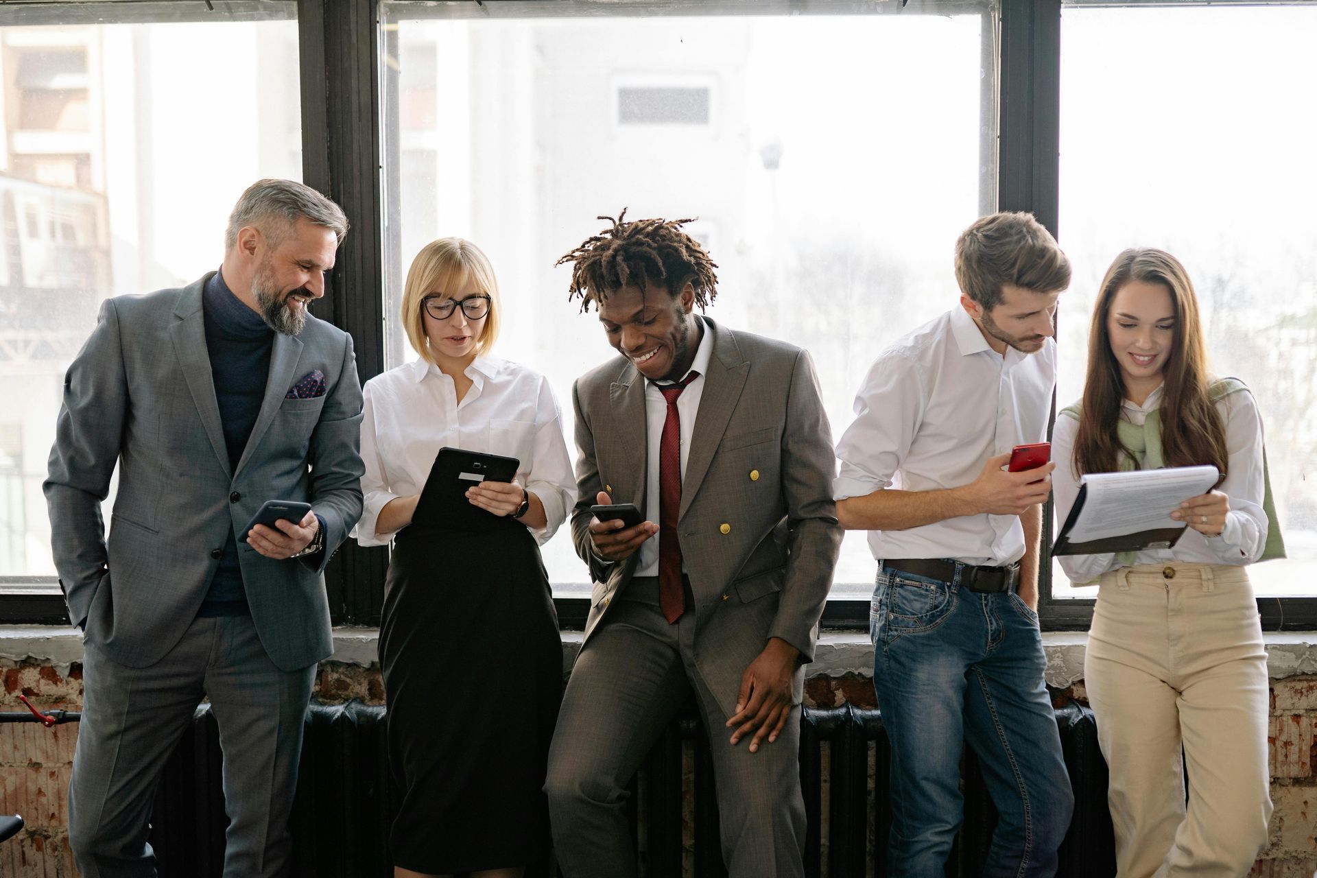 A group of business people are standing next to each other in front of a window.