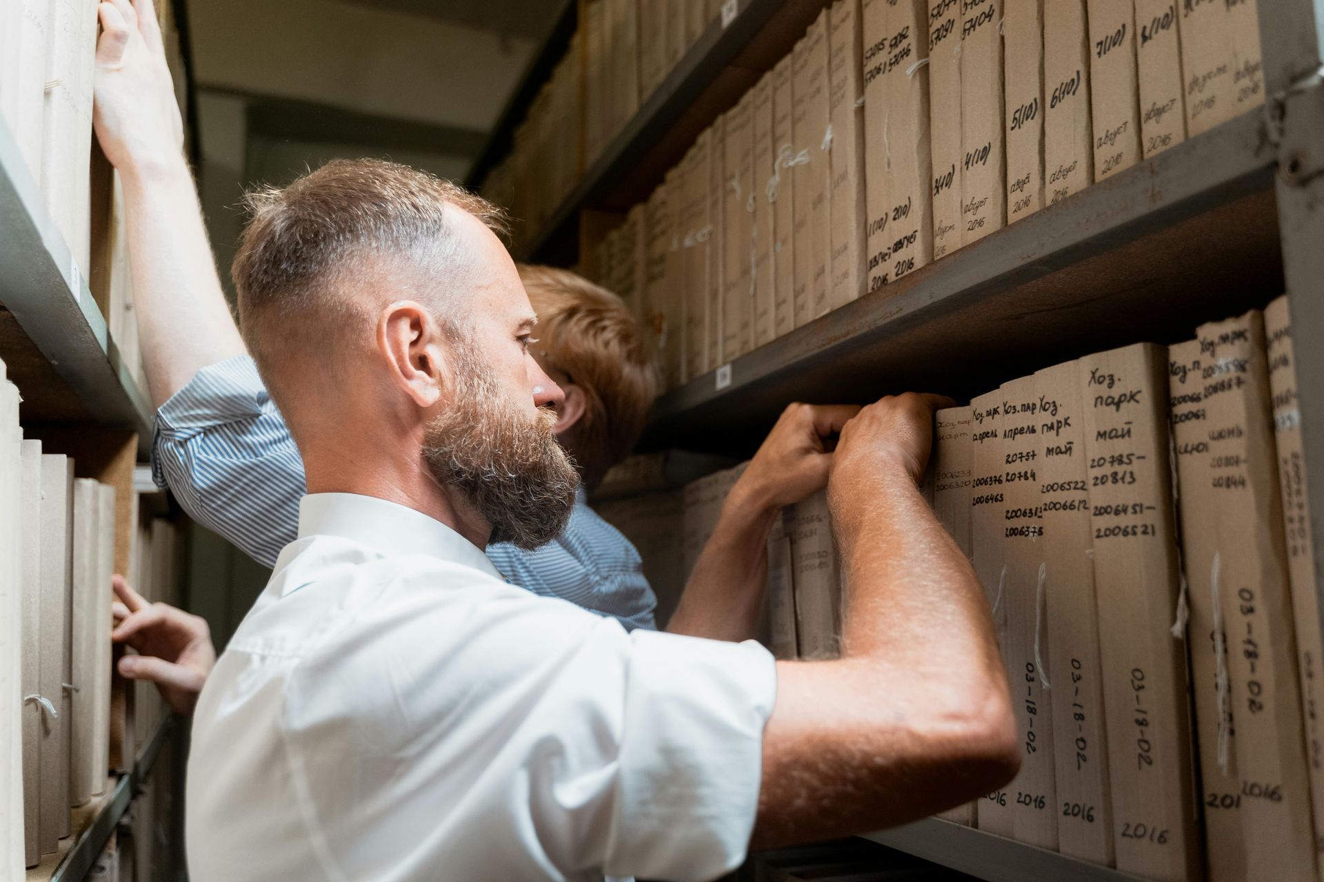A man and a boy are looking at a shelf in a library.