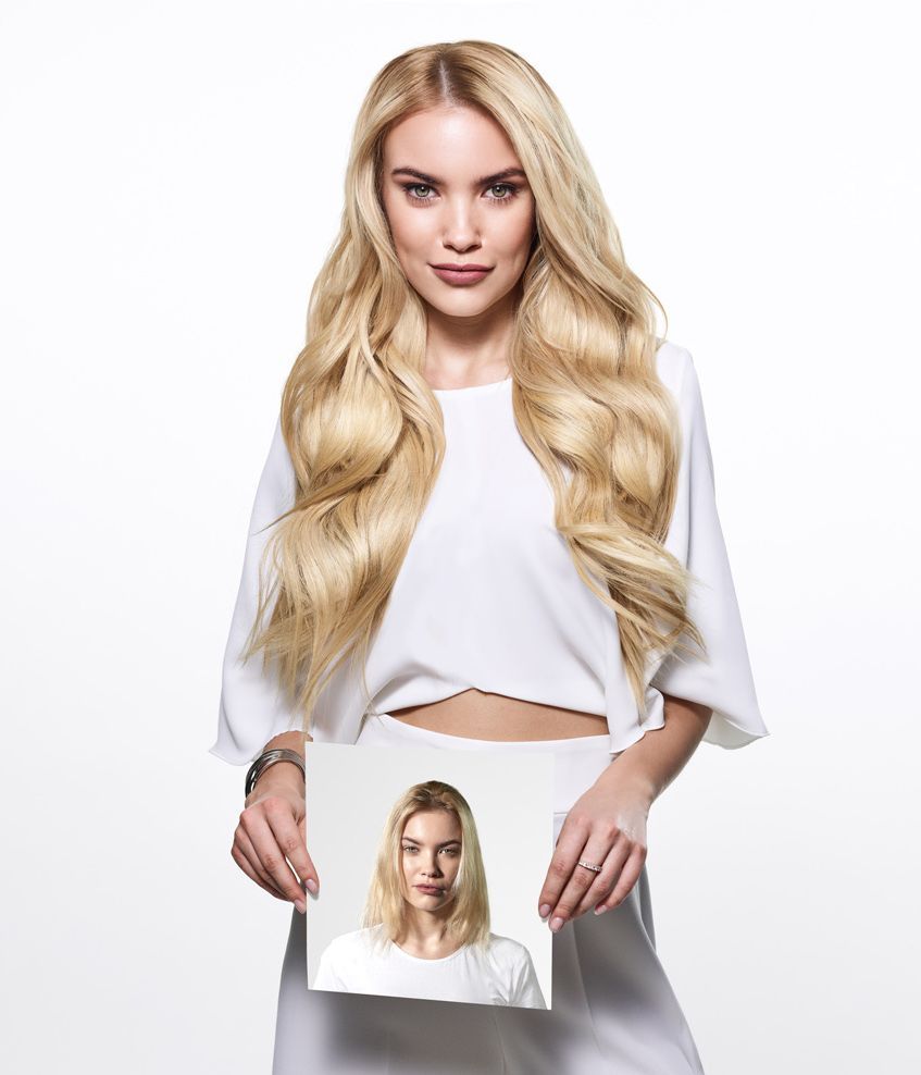 Blonde woman in a white outfit holding a small photo of herself against a white background
