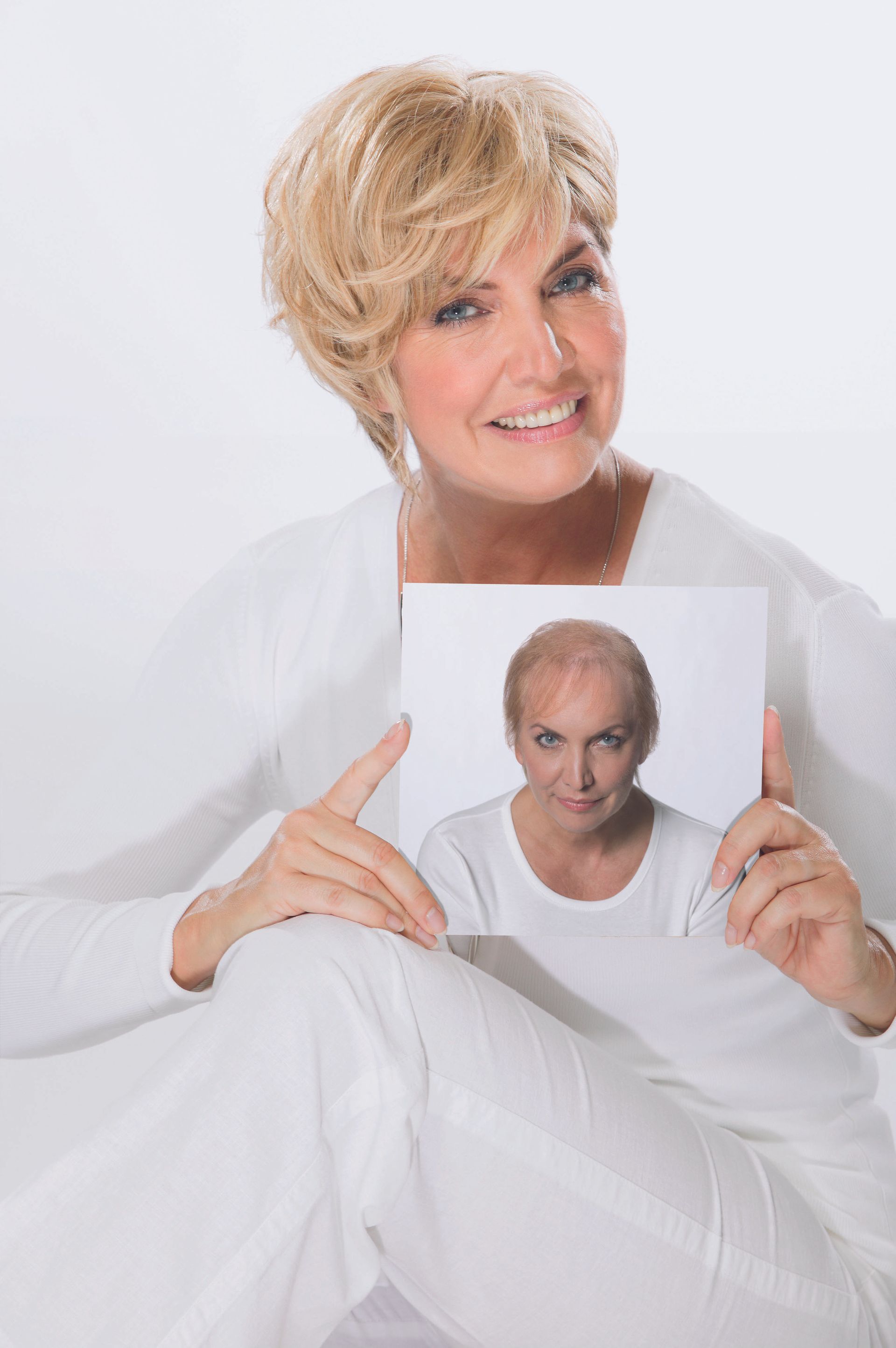 Woman holding a photo of a bald man, seated against a light background