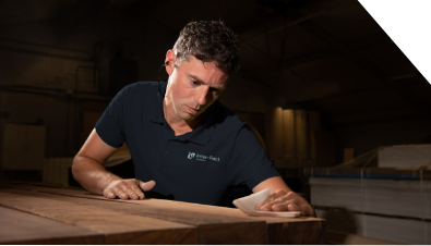 A man in a blue shirt is sanding a piece of wood.