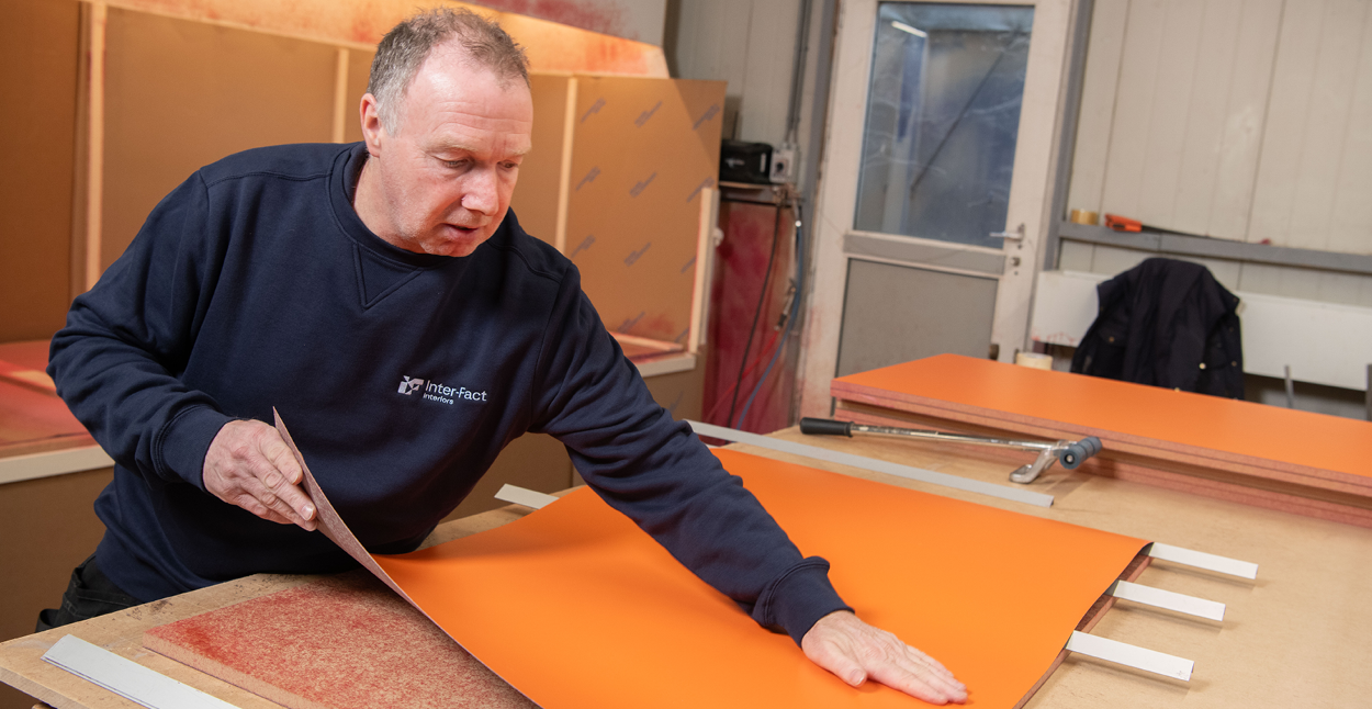 A man in a blue shirt is sanding a piece of wood
