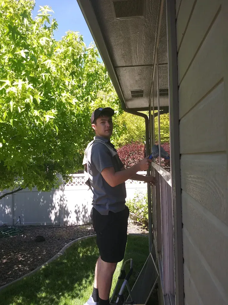 Man on ladder installing something on house exterior.
