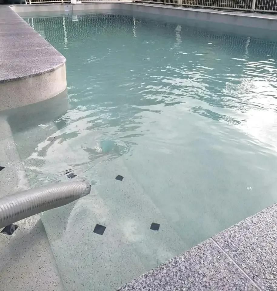 A swimming pool with a hose attached to the edge