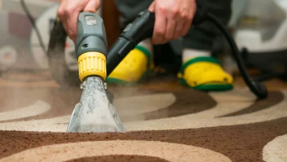 Person using hand held vacuum suctioning water from wet carpet.