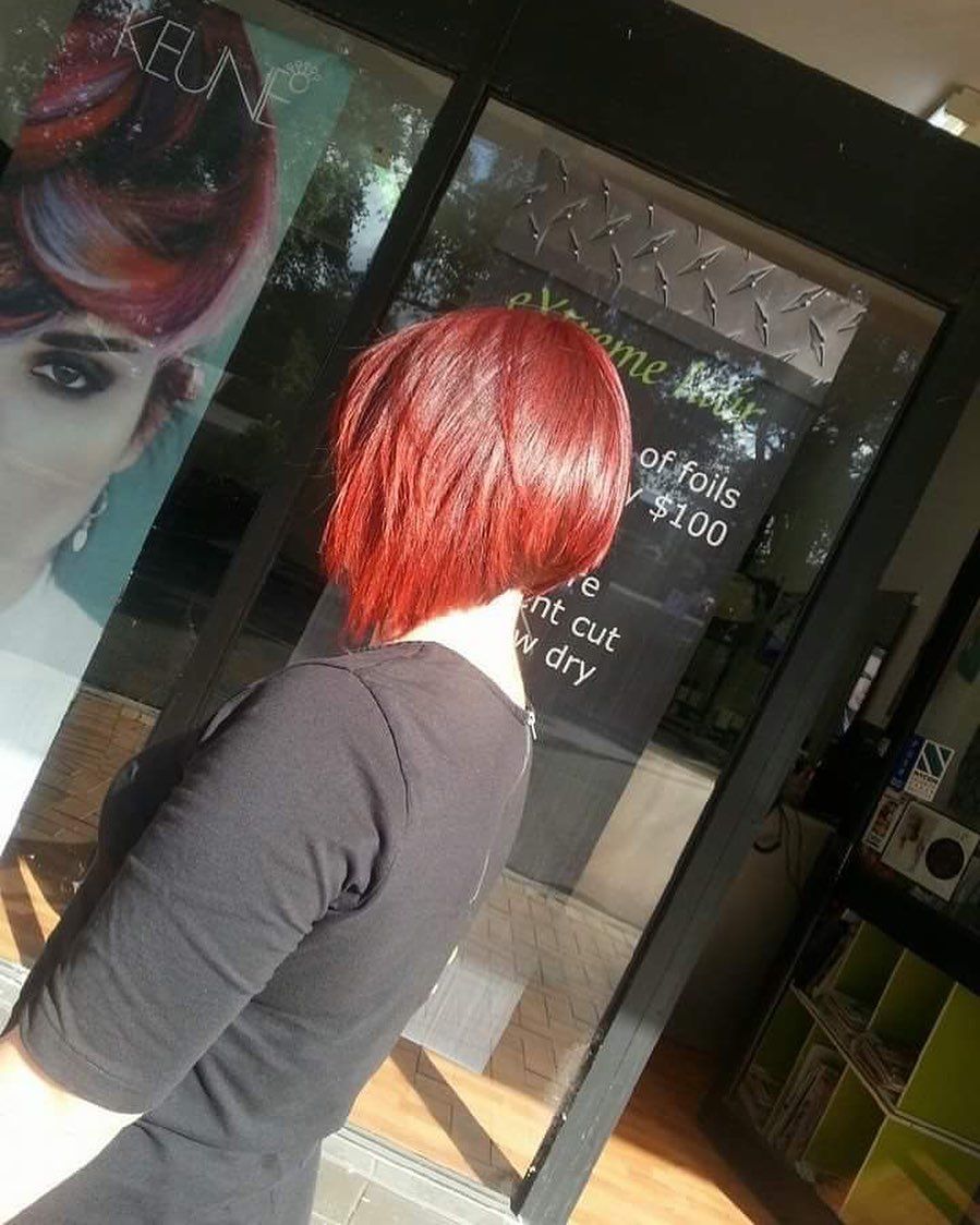 A Woman With Red Hair is Standing in Front of a Keune Sign — Innovative Hair Salon in Gosford, NSW