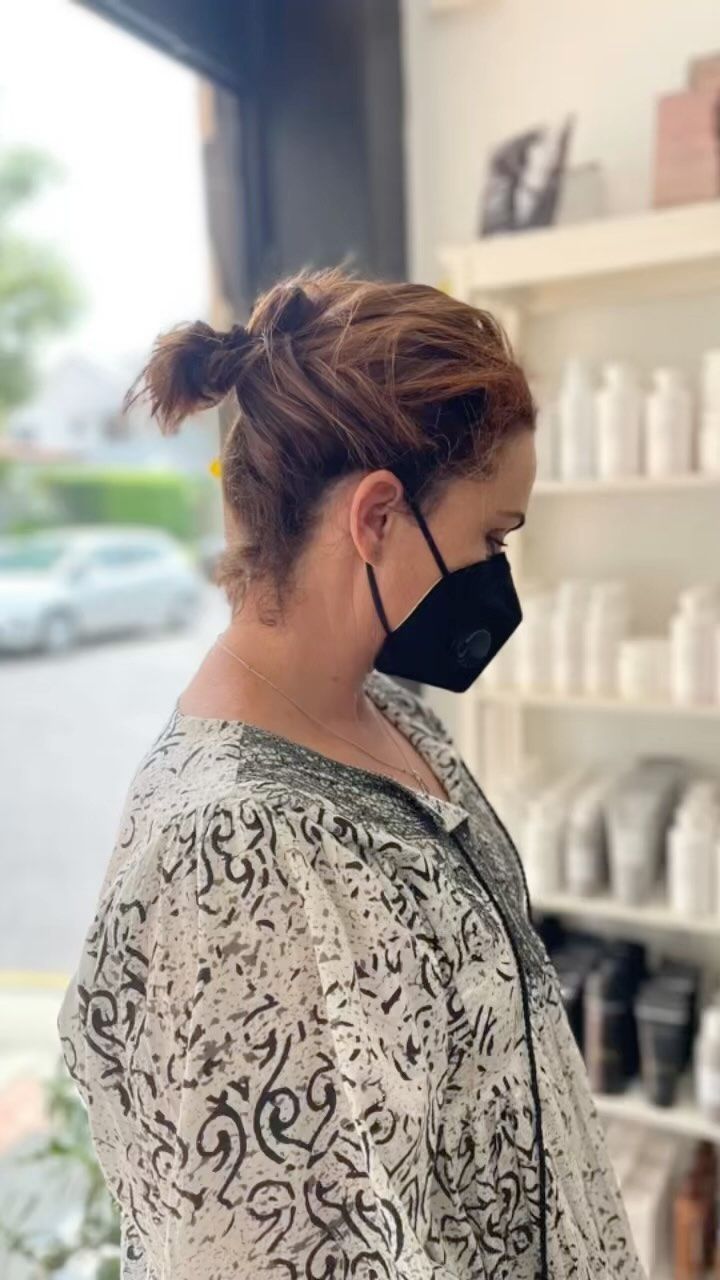 A Woman Wearing a Face Mask is Standing in a Store — Innovative Hair Salon in Gosford, NSW
