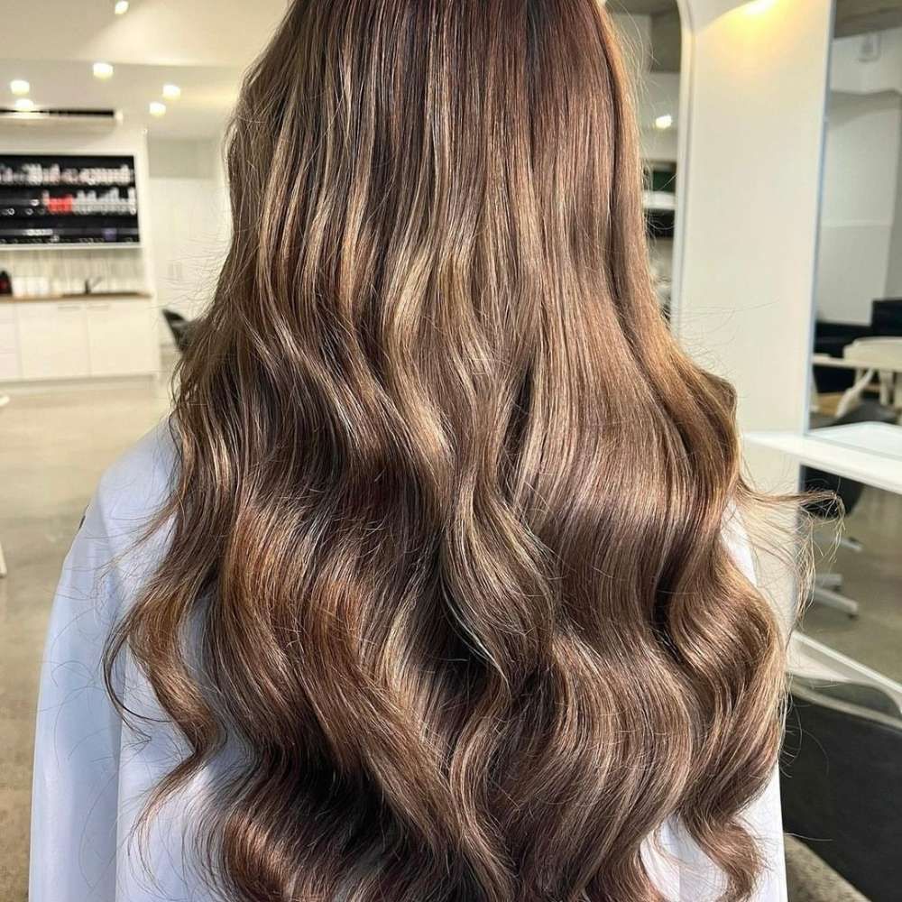 A Woman With Long Brown Hair is Sitting in a Salon — Innovative Hair Salon in Gosford, NSW