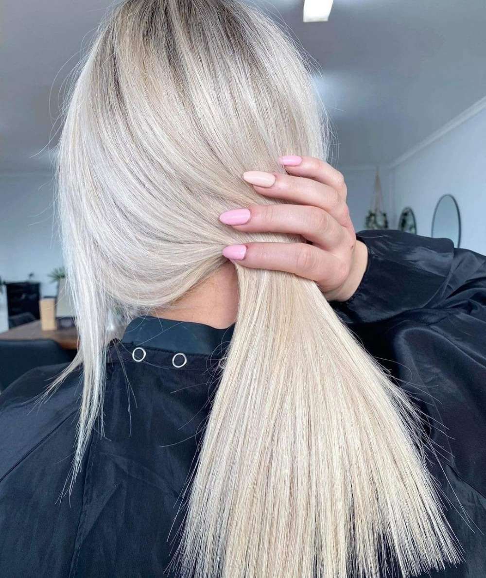 A Woman With Blonde Hair and Pink Nails Holds Her Hair — Innovative Hair Salon in Gosford, NSW