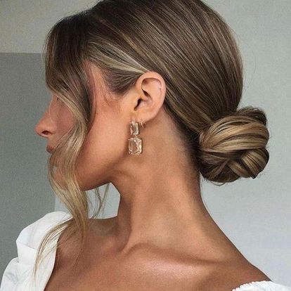 A Woman is Wearing a Bun and Earrings — Innovative Hair Salon in Gosford, NSW