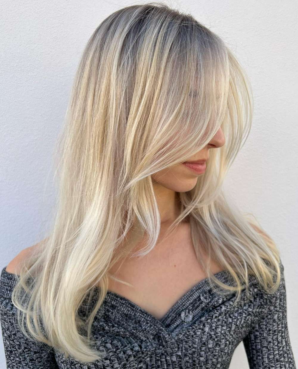 A Woman With Long Blonde Hair is Wearing a Grey Sweater — Innovative Hair Salon in Gosford, NSW