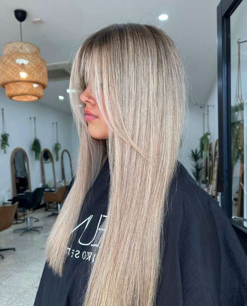 A Woman With Long Blonde Hair is Wearing a Black Cape — Innovative Hair Salon in Gosford, NSW