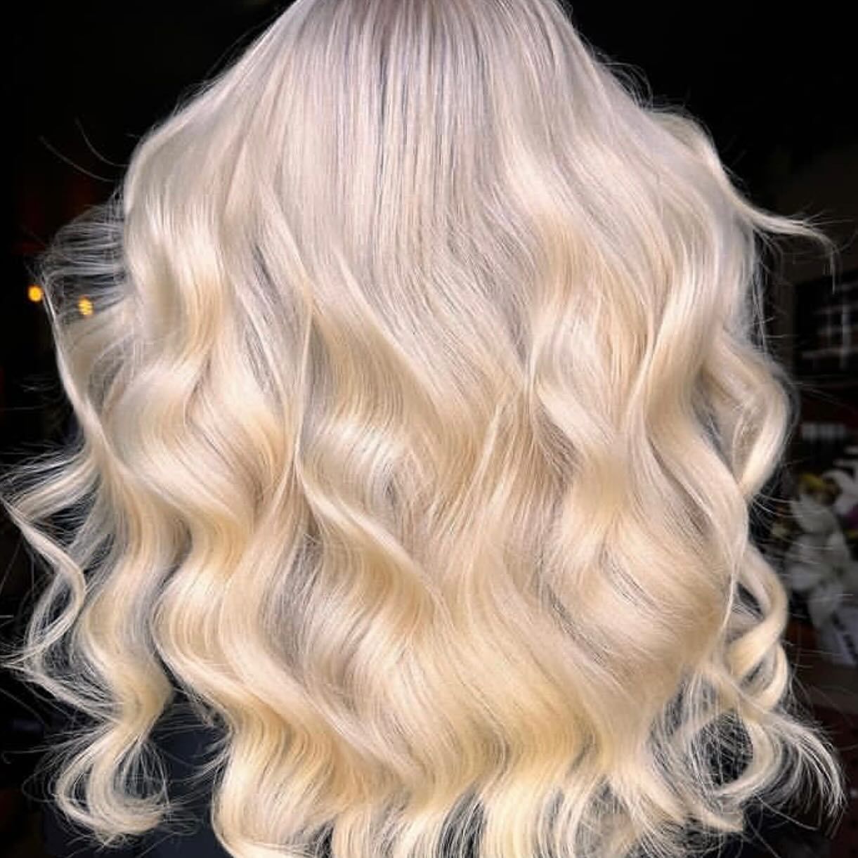 A Woman With Long Blonde Hair is Wearing a Black Shirt — Innovative Hair Salon in Gosford, NSW