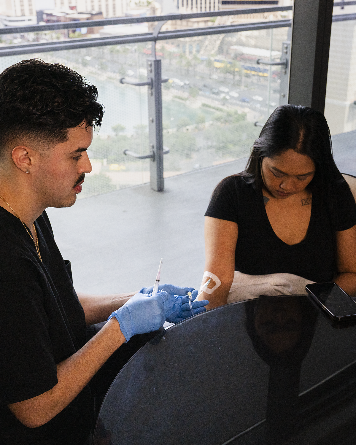 Two people wearing gloves handle an object at a glossy table indoors, with one person focused on writing or examining it.