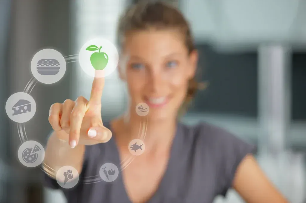 Person touching a glowing green apple icon on a digital interface, with blurred charts in the background