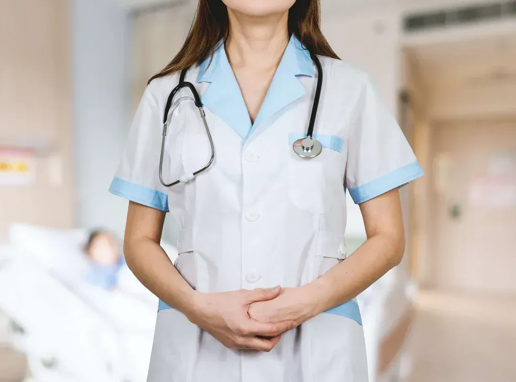 Healthcare worker in white uniform with stethoscope standing in a hospital hallway