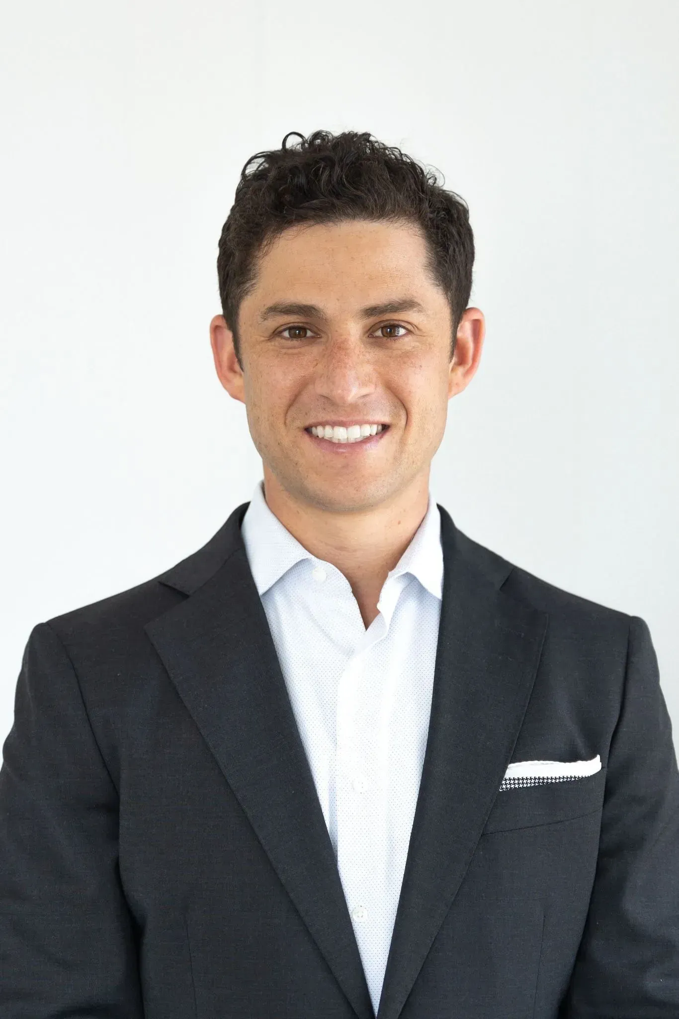 A man in a suit and white shirt is smiling for the camera.