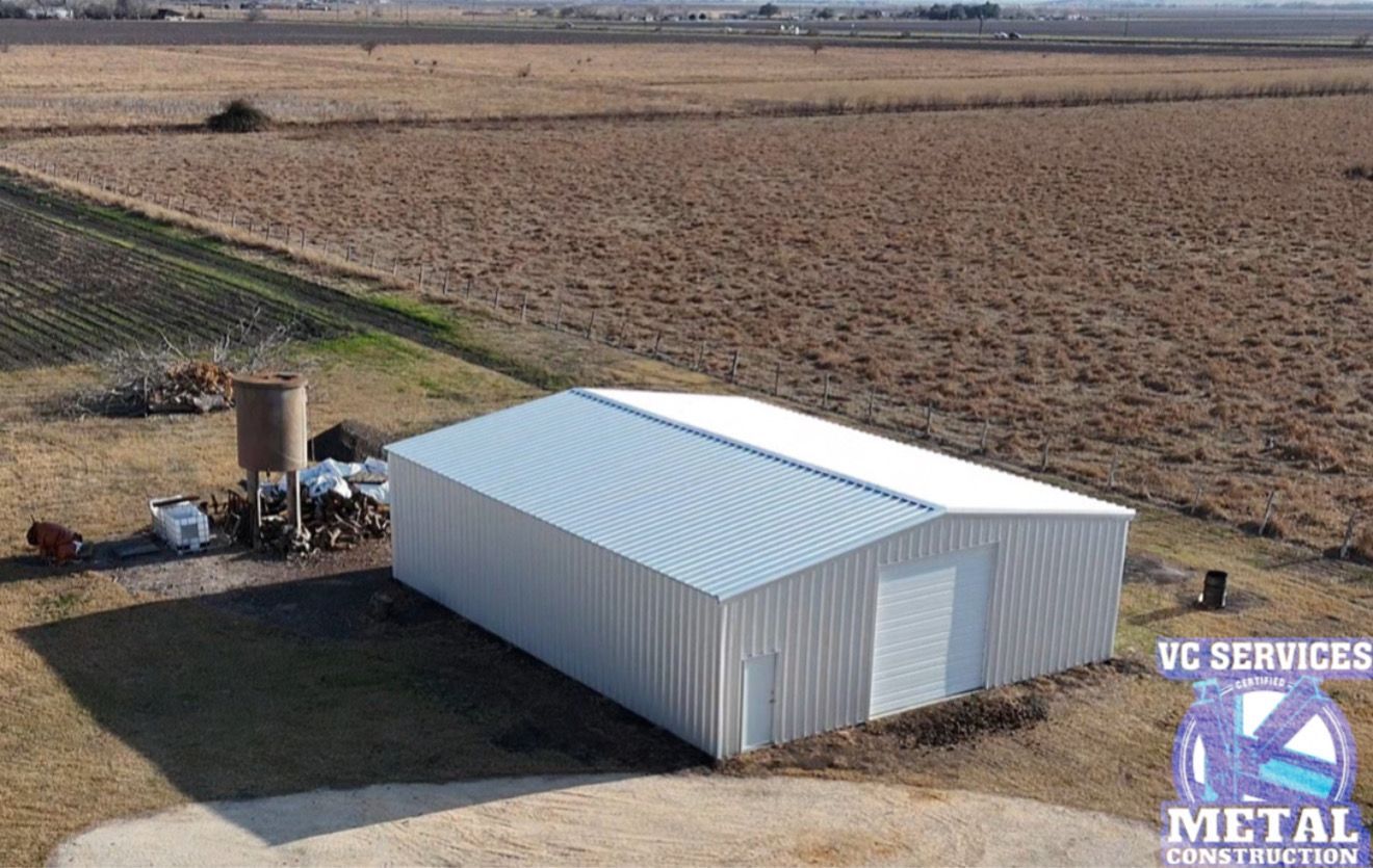 White metal shed beside farm equipment in a plowed field