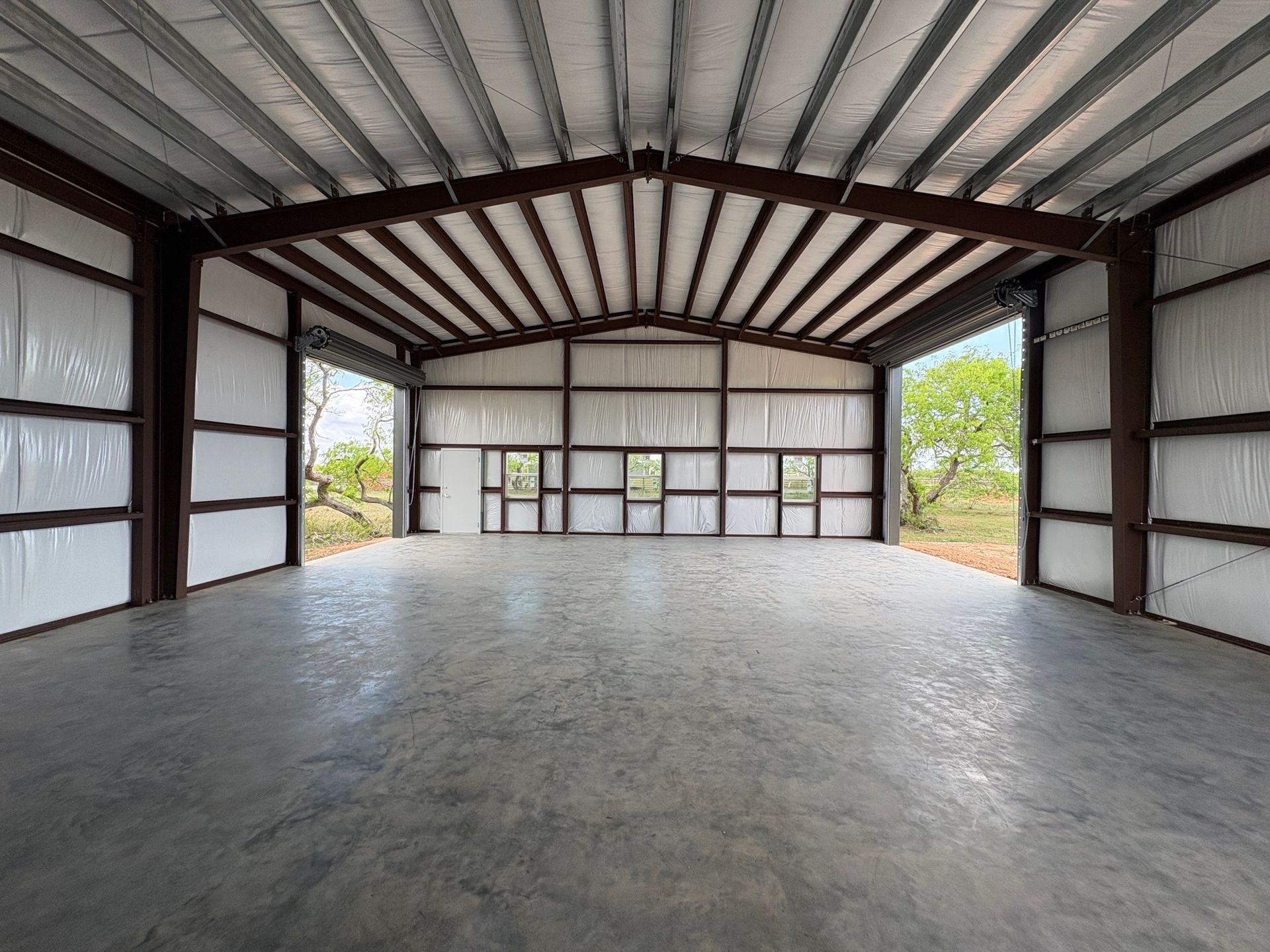 Empty metal workshop interior with concrete floor and open side walls