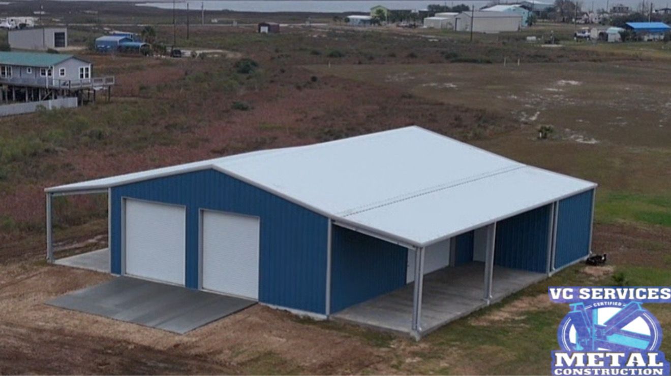 Blue metal warehouse with white roof and roll-up doors on a bare lot