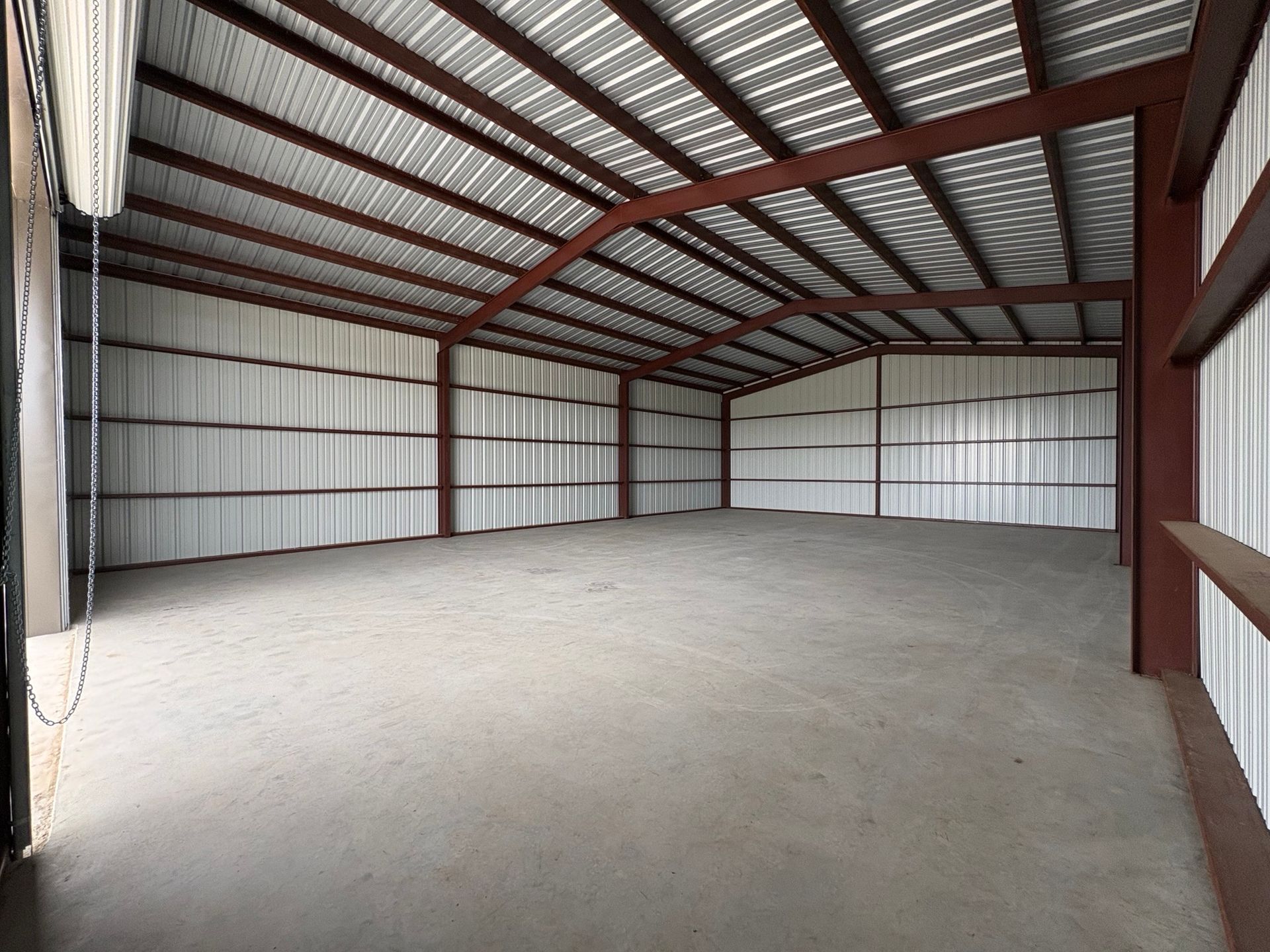 Empty metal warehouse interior with concrete floor and exposed steel roof beams