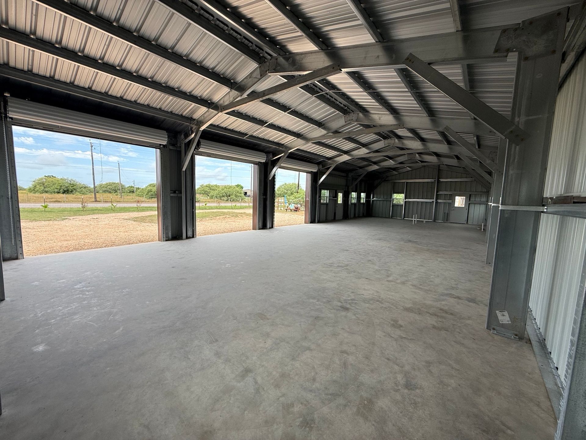 Empty covered warehouse interior with corrugated metal roof and open sides overlooking fields