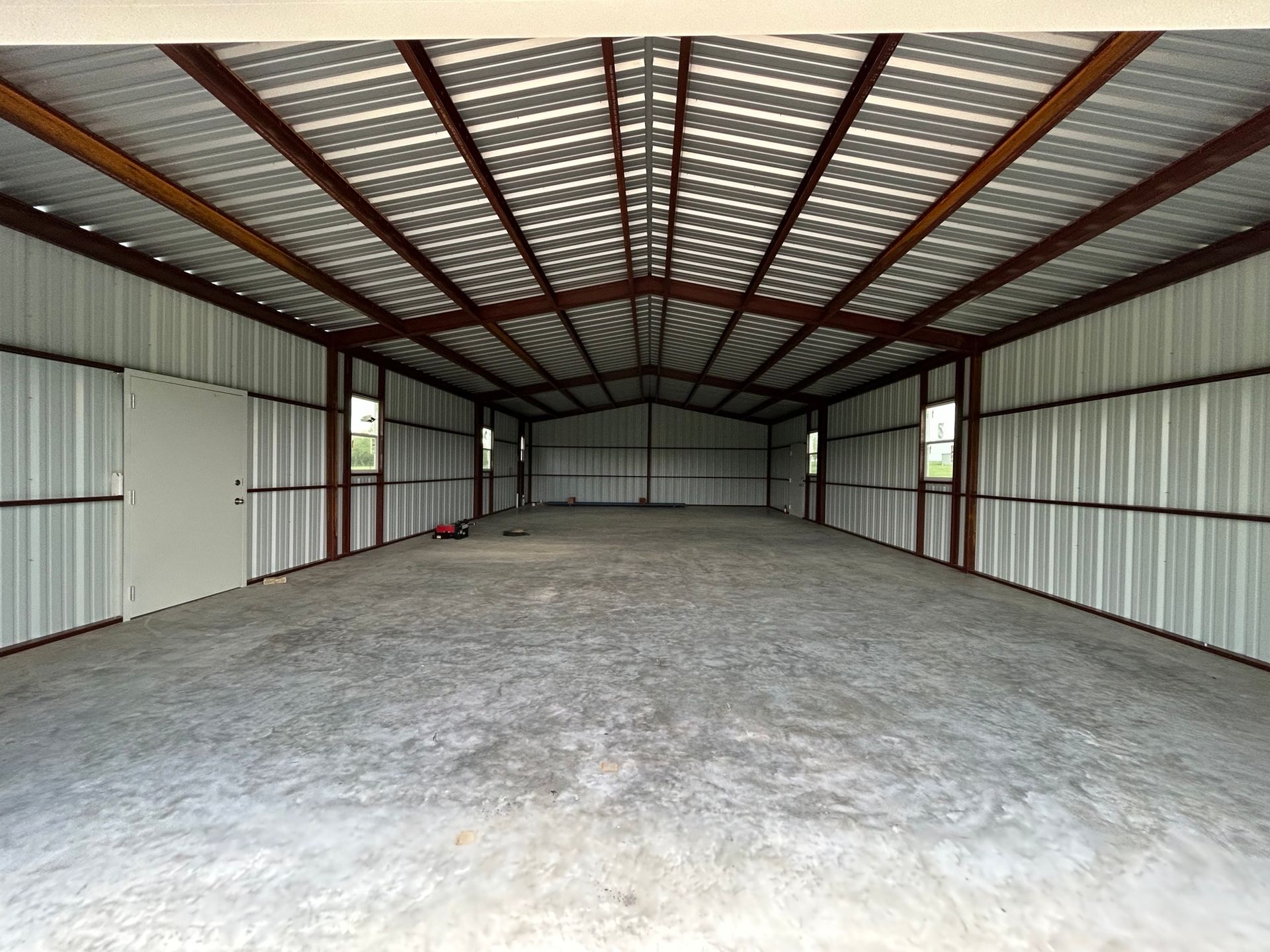 Empty metal storage shed with a concrete floor and a vaulted roof