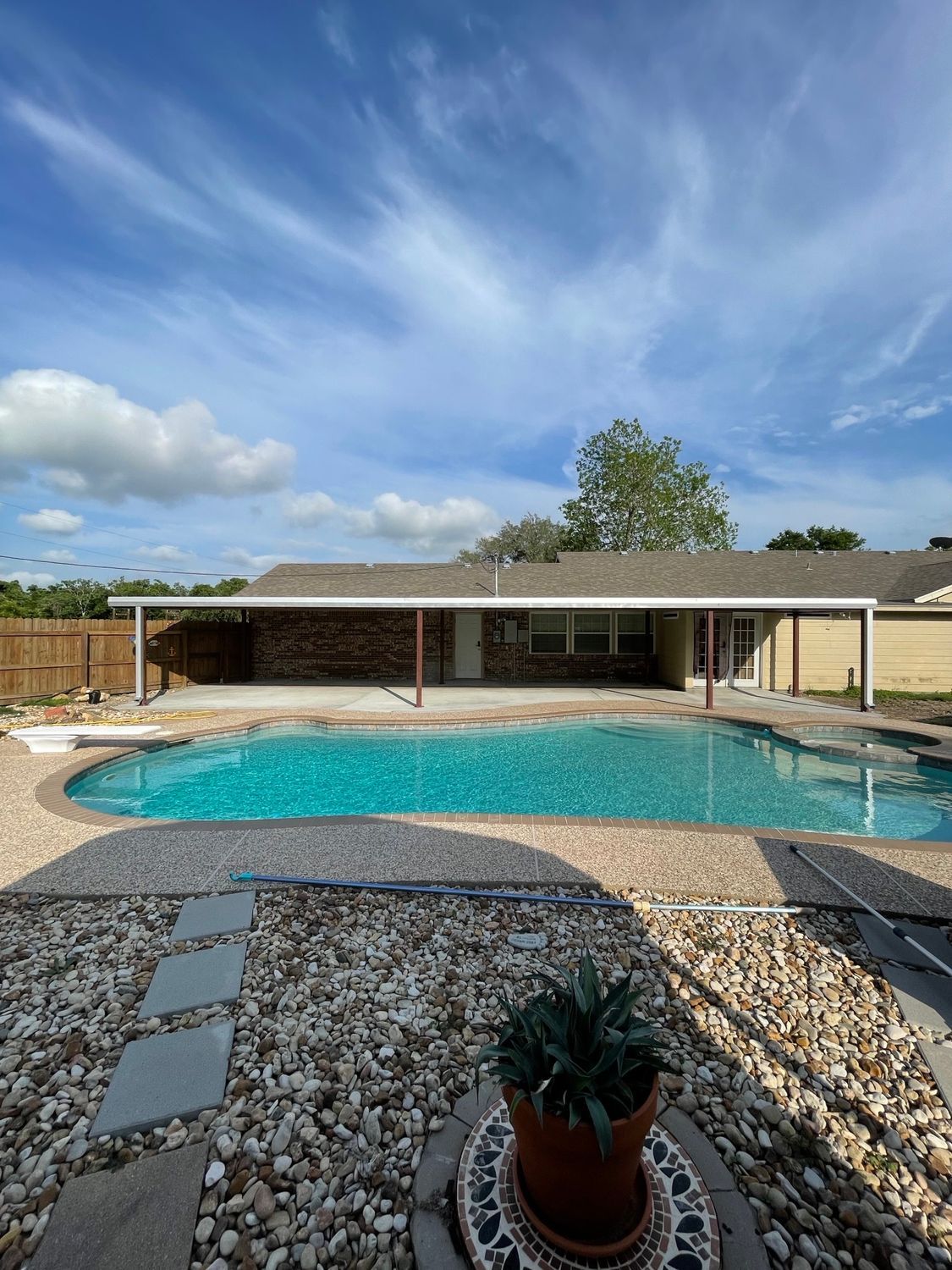 Backyard swimming pool with patio, covered seating area, and blue sky overhead