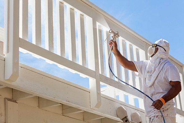 House painter spray painting a deck of a home — La Selva Beach, CA — J's Custom Painting House painter spray painting a deck of a home — La Selva Beach, CA — J's Custom Painting