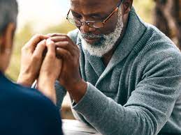 a man with glasses is praying with another man .
