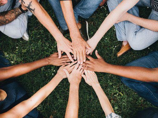 a group of people are putting their hands together in a circle .