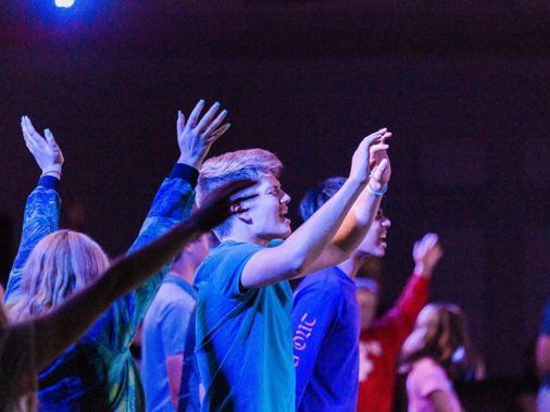 a group of people are standing in a dark room with their hands in the air .