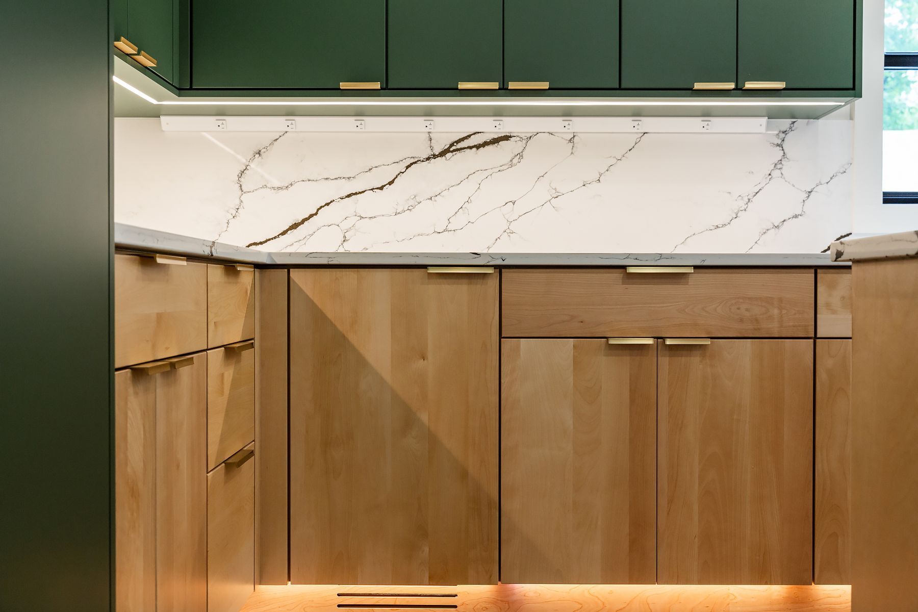 Modern kitchen with green cabinets, wood lower cabinets, and marble backsplash.