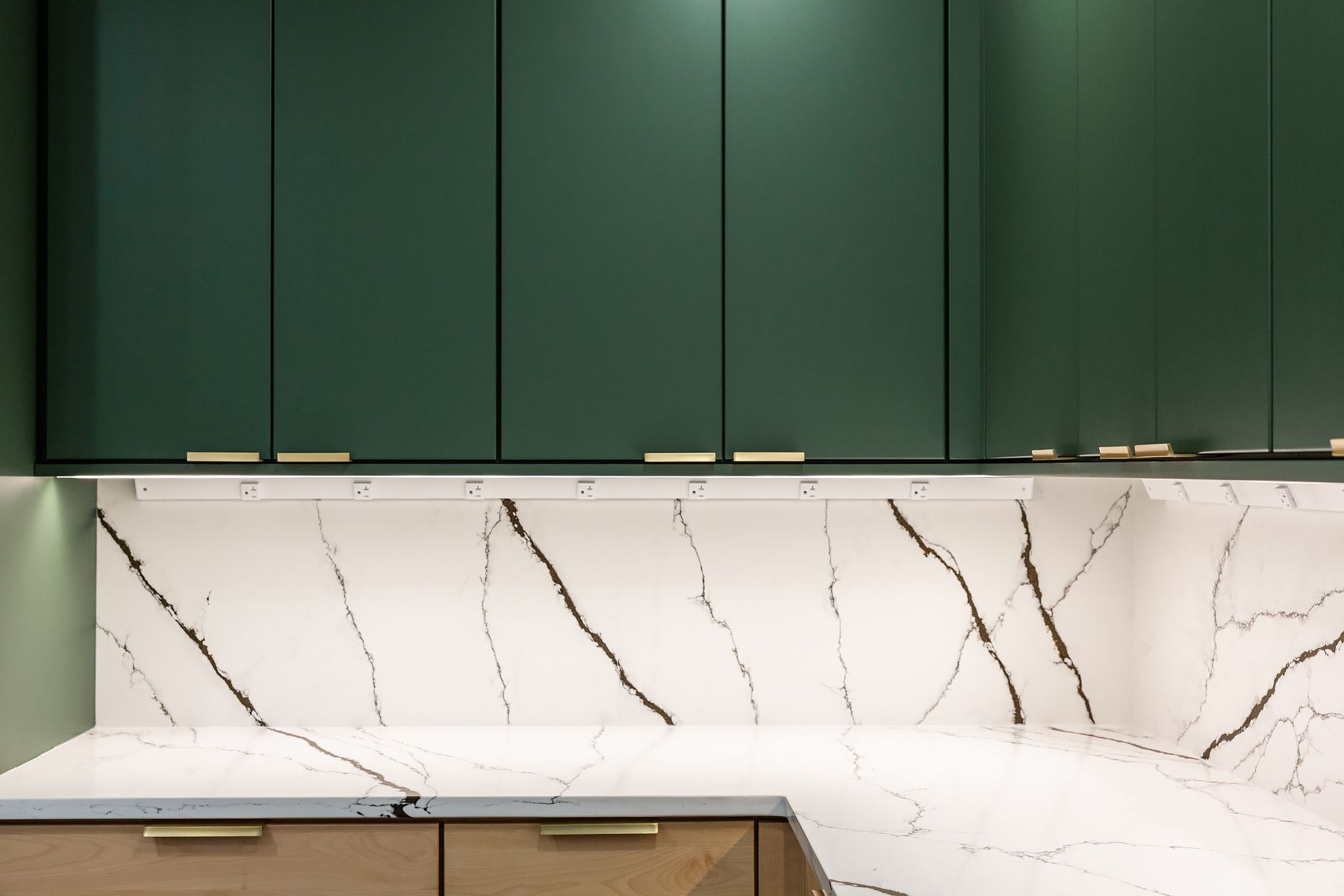 Modern kitchen with dark green cabinets and white marble backsplash countertops