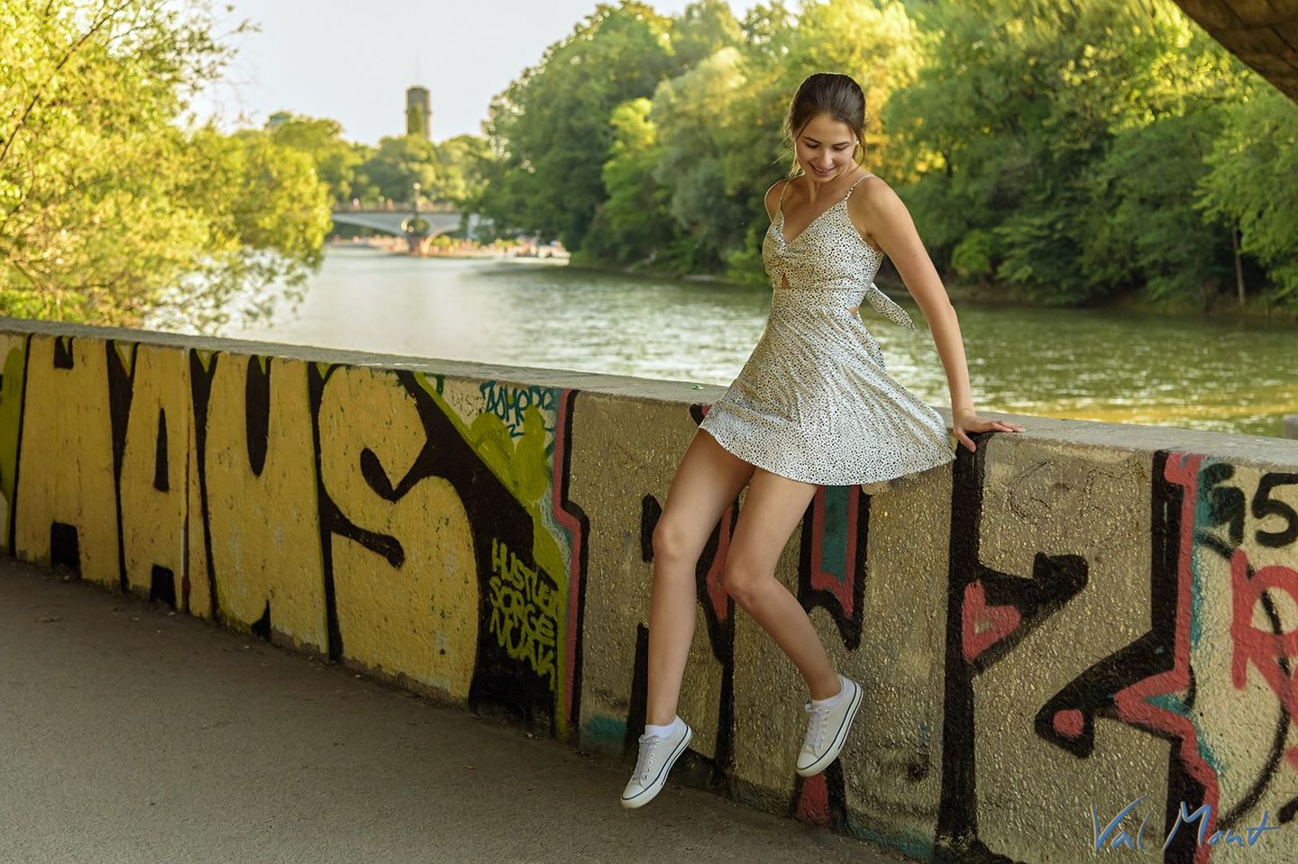 mädchen annika im kurzen sommerkleid an der isar in münchen hüpft von der mauer