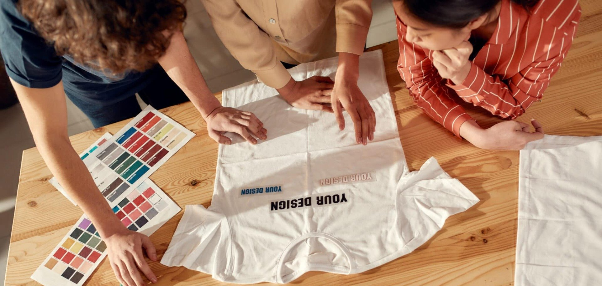 A group of people are sitting around a table looking at a t-shirt.