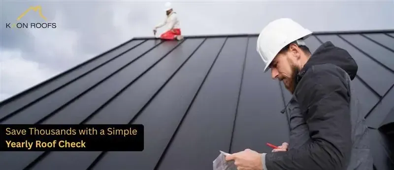 Roof inspector in a white hard hat examines a dark metal roof, with text promoting a yearly roof check.