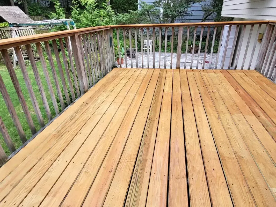 Wooden deck with railings overlooking a green backyard and trees